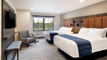A hotel room with two beds, a bench, a TV, and a large window.