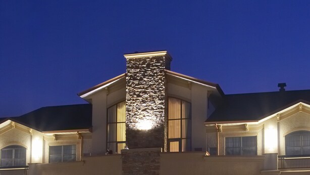 A large, two-story building with a stone facade and multiple windows, illuminated by warm lighting. - Clubhouse Hotel Suites Sioux Falls (Sioux Falls)