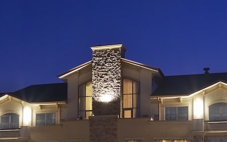 A large, two-story building with a stone facade and multiple windows, illuminated by warm lighting.