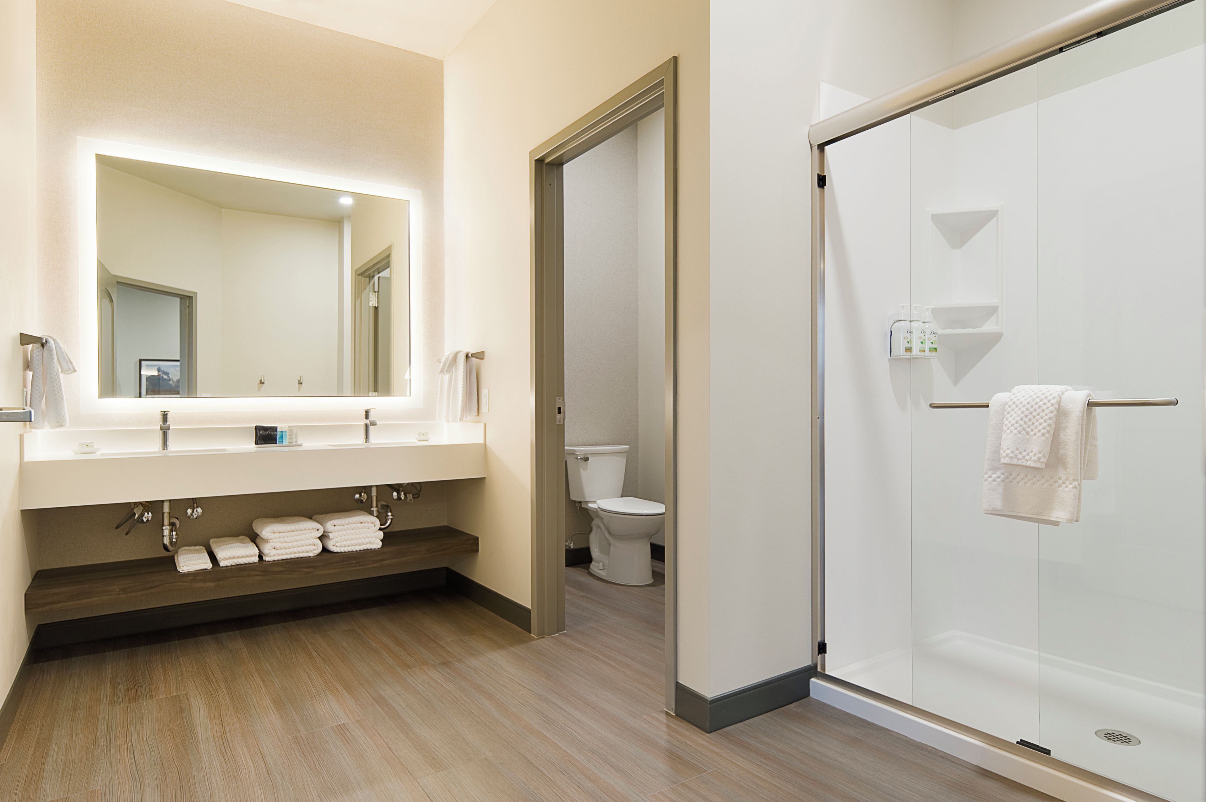A modern bathroom with a large mirror, a shower, and a toilet.