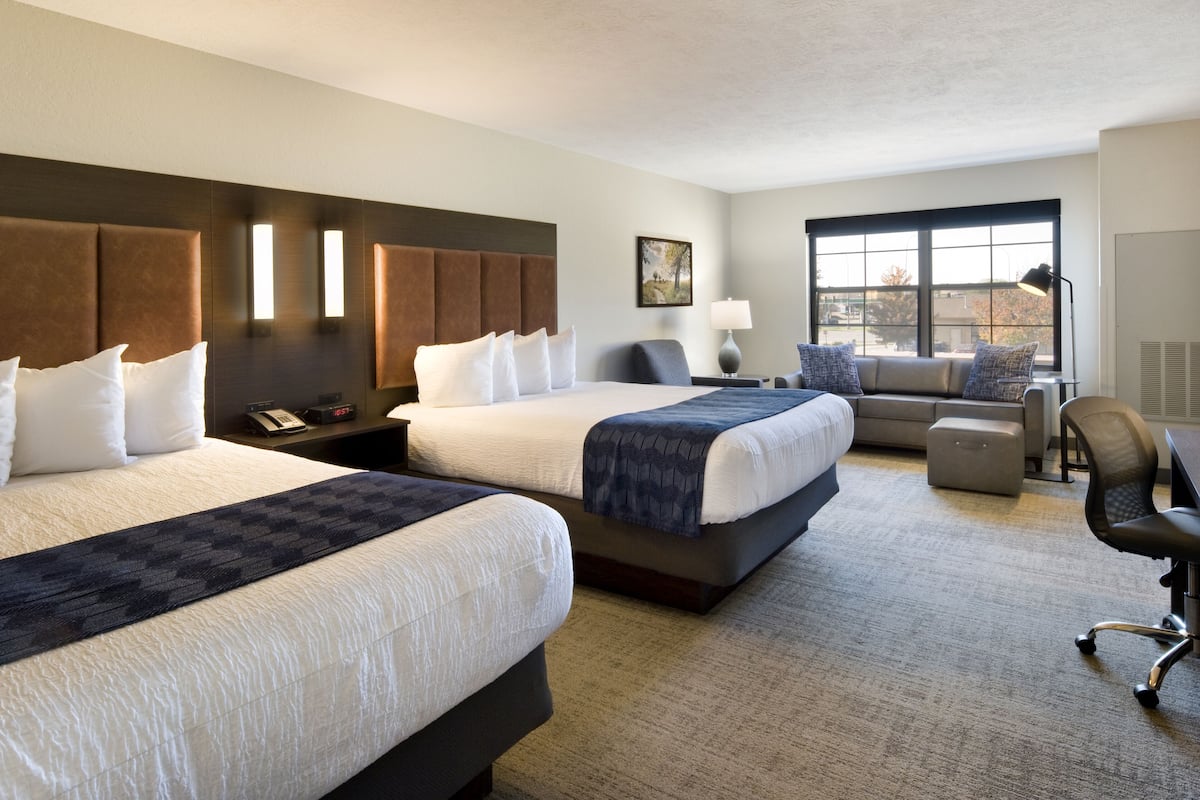 Une chambre d’hôtel avec deux lits, un bureau, une chaise et une fenêtre.