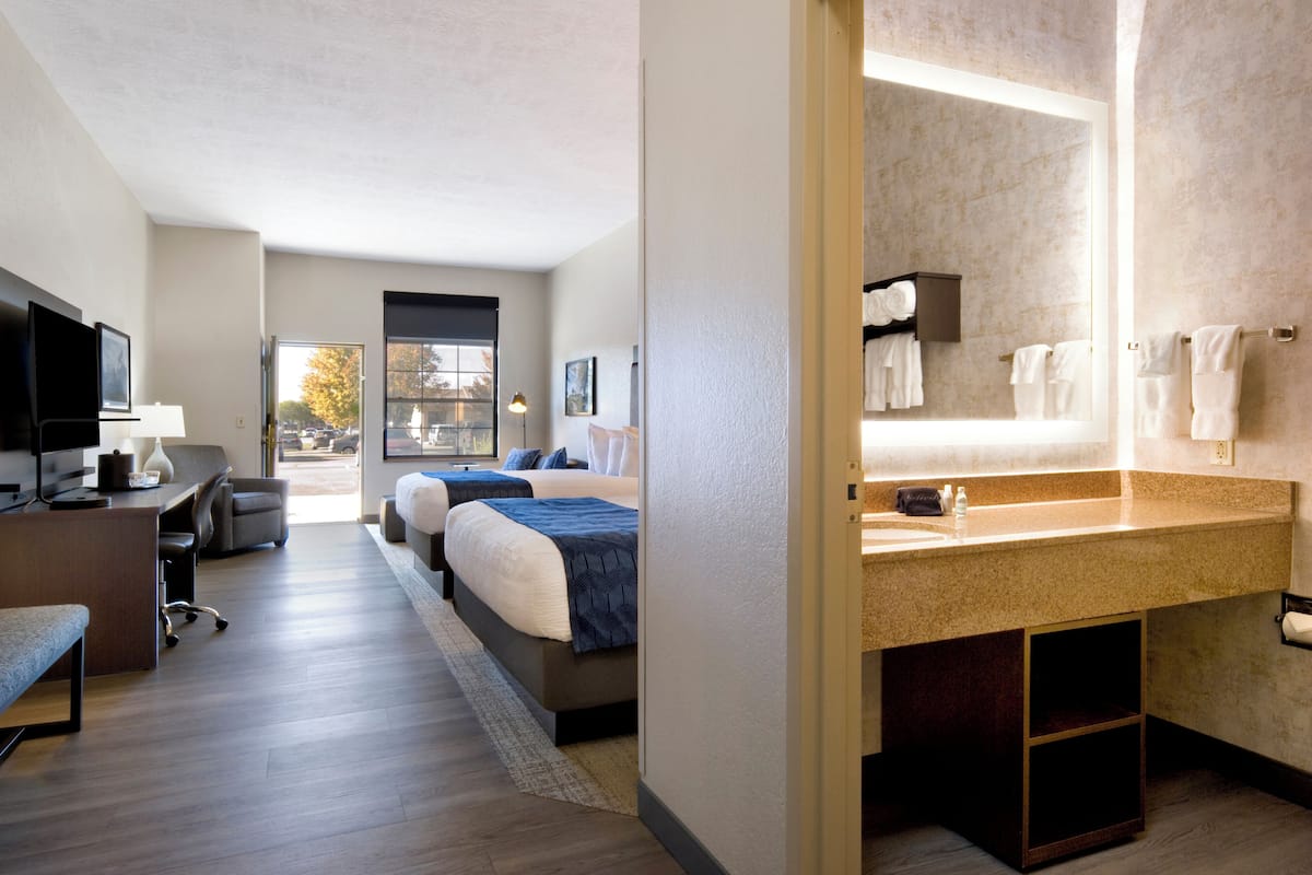 Une chambre d’hôtel équipée d’un lit, d’un bureau, d’une chaise, d’une télévision et d’une salle de bain avec un lavabo et un porte-serviettes.