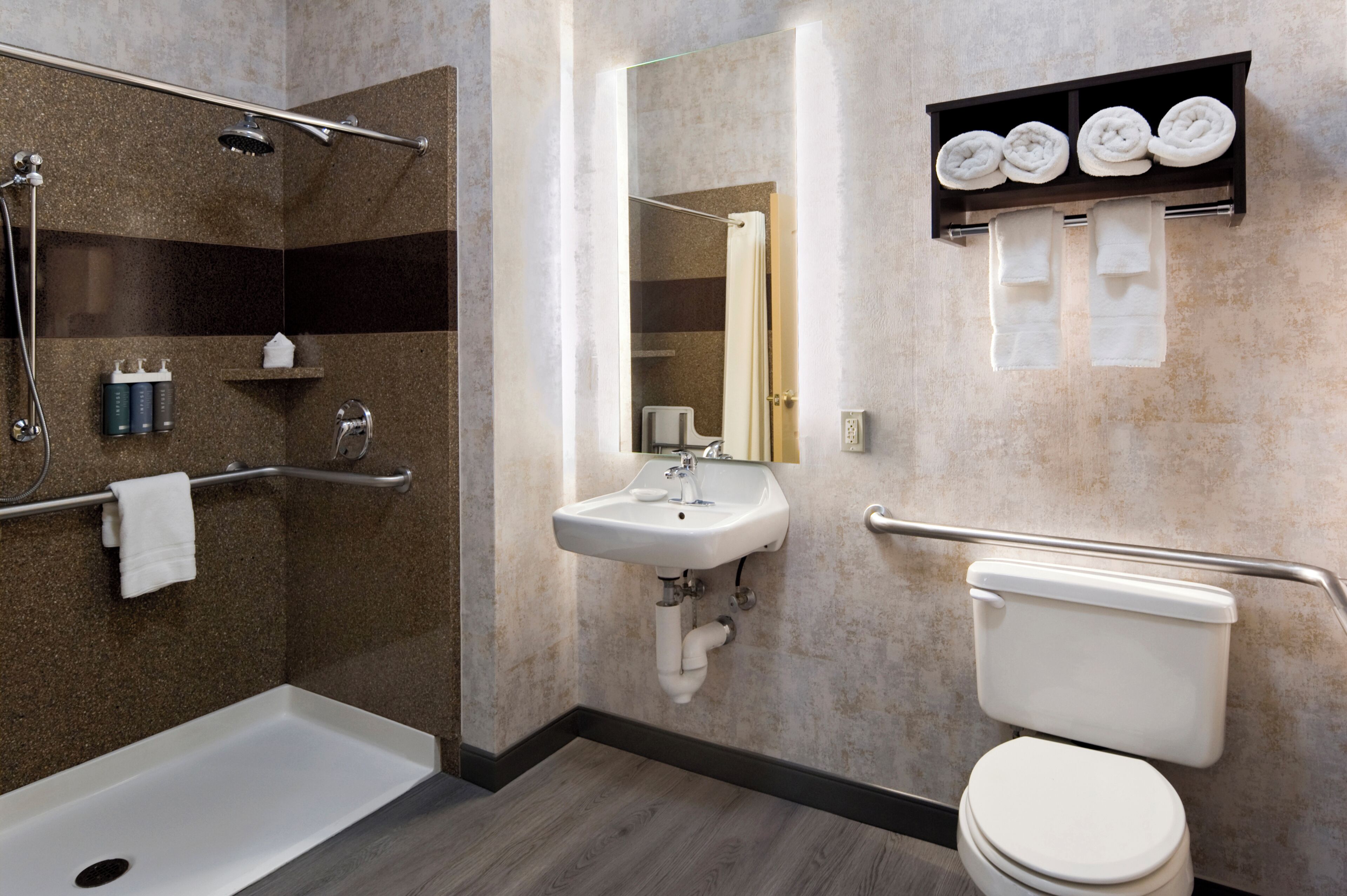 A modern bathroom with a shower, sink, toilet, and towel rack.