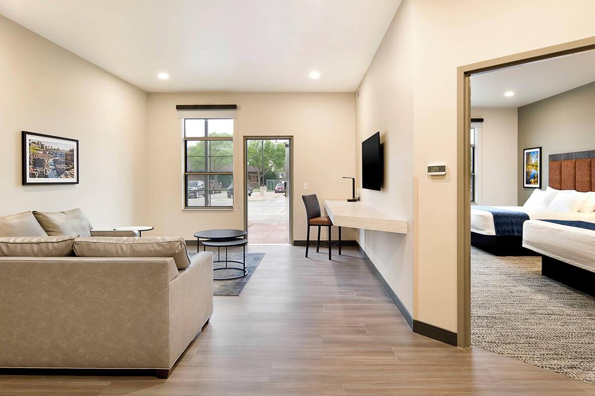 Une chambre d’hôtel moderne équipée d’un canapé, d’un bureau, d’un lit et d’un téléviseur fixé au mur.