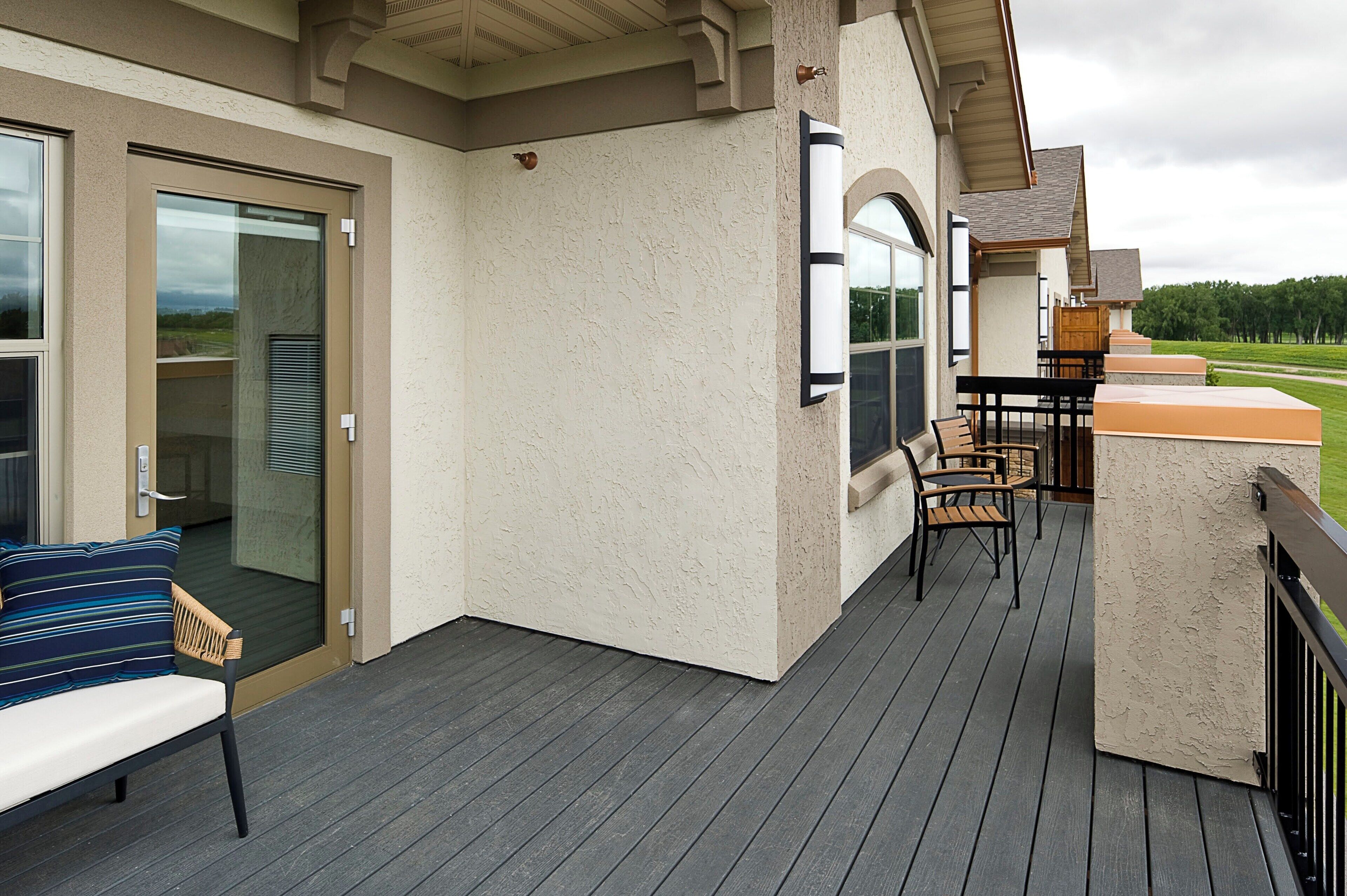 A covered deck with a bench and chairs, a glass door, and a view of the landscape.