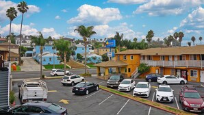 A parking lot with various cars, a building with a sign for Radisson Inn & Suites, and a view of residential buildings in the background.