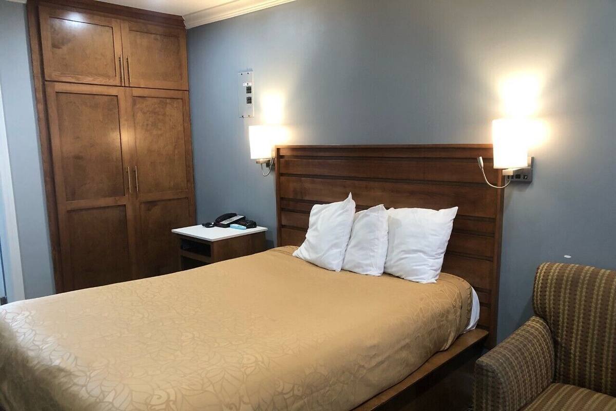 Una habitación de hotel con cama, mesita de noche, silla y armario.