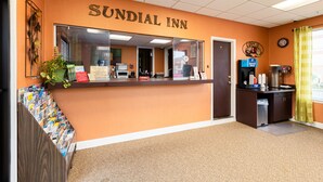 A reception desk at Sundial Inn with a mirror, a clock, and a coffee machine.
