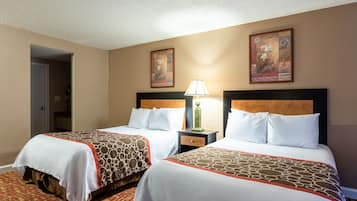 A hotel room with two beds, a nightstand with a lamp, and a door leading to another room.