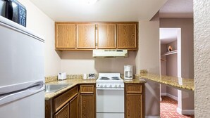 A compact kitchen with wooden cabinets, a white stove, and a granite countertop.