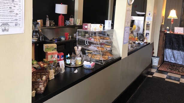 Un mostrador de café con menú, pastelería y condimentos.