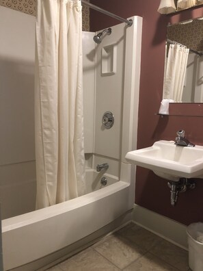 Un baño con ducha, lavamanos y espejo.
