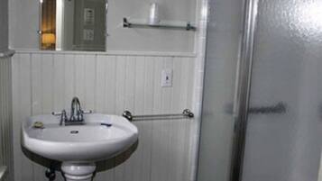 A bathroom with a pedestal sink, a mirror above it, a towel rack, and a shower with a glass door.