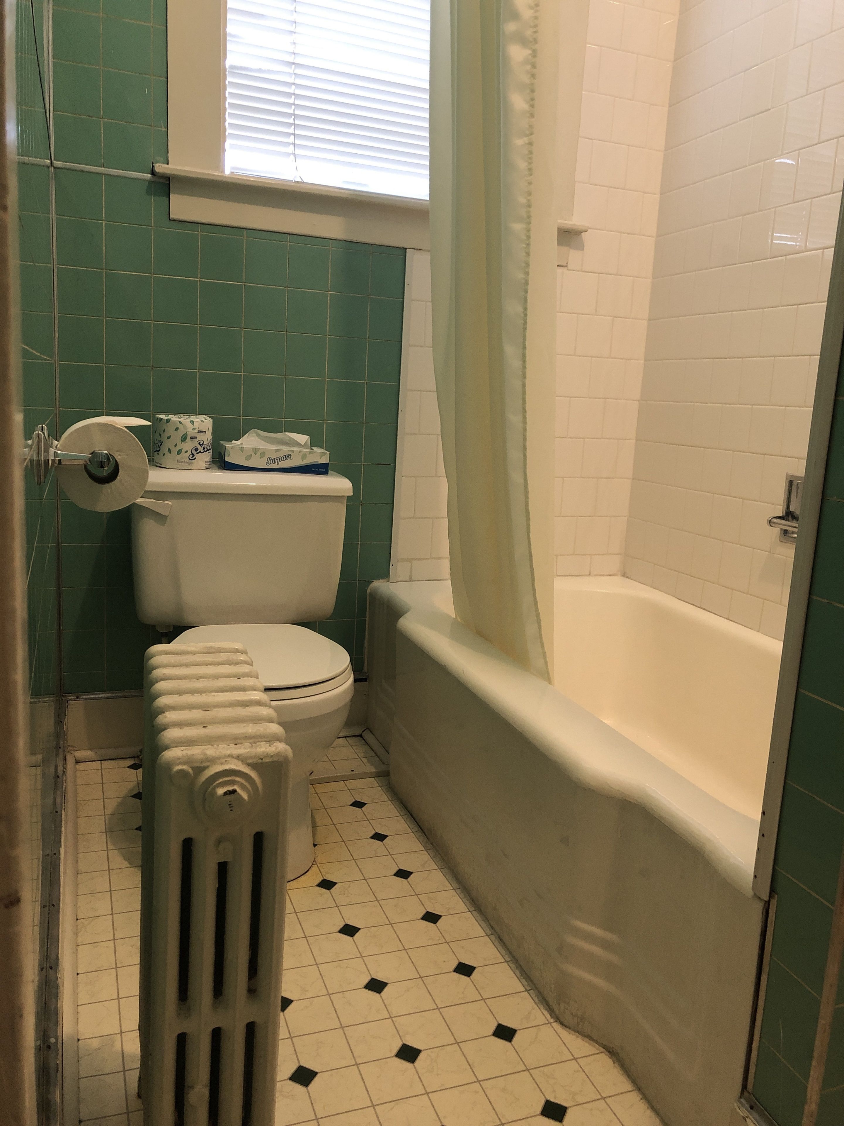 A bathroom with a toilet, a radiator, and a bathtub.