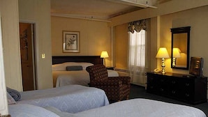 Una habitación de hotel con dos camas, una silla, un tocador y un espejo.