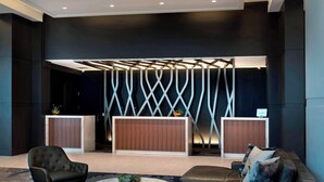En moderne lobby med reception, siddeområde og dekorative vægpaneler.