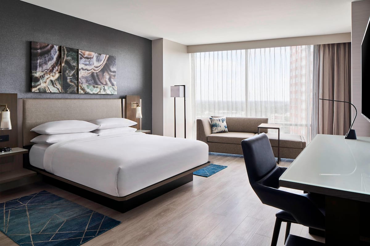 Une chambre d’hôtel avec un grand lit, un canapé, un bureau et une télévision.