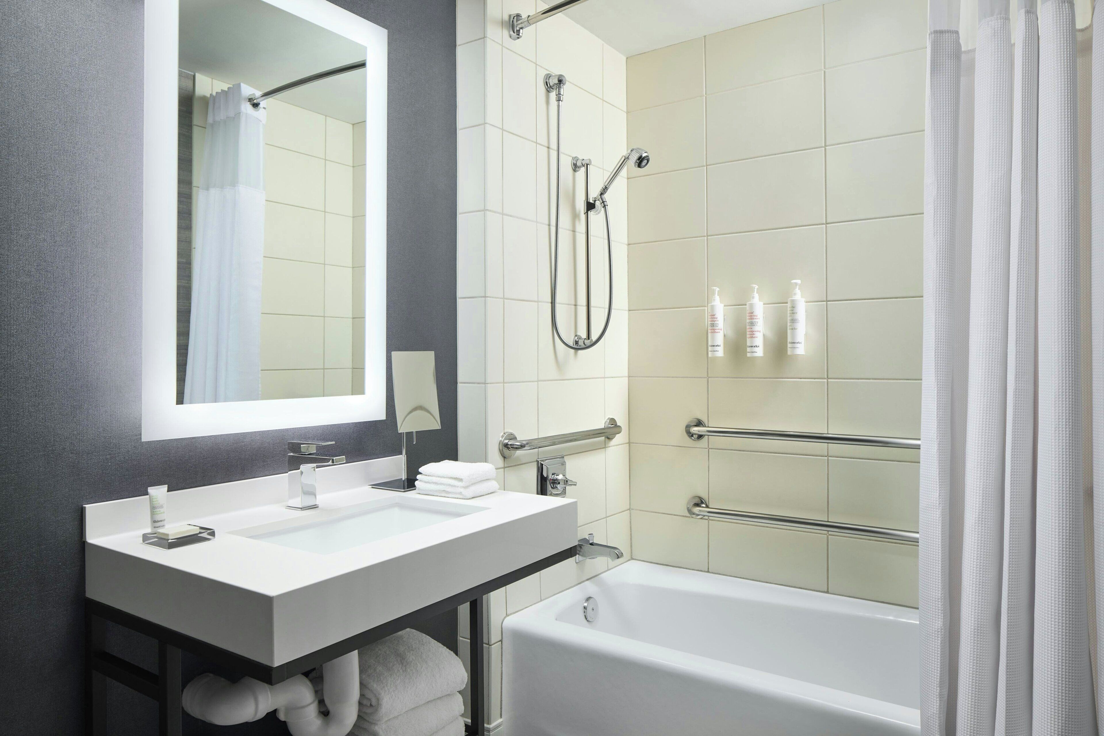 A modern bathroom with a white sink, mirror, and bathtub.