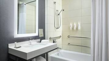 A modern bathroom with a white sink, mirror, and bathtub.
