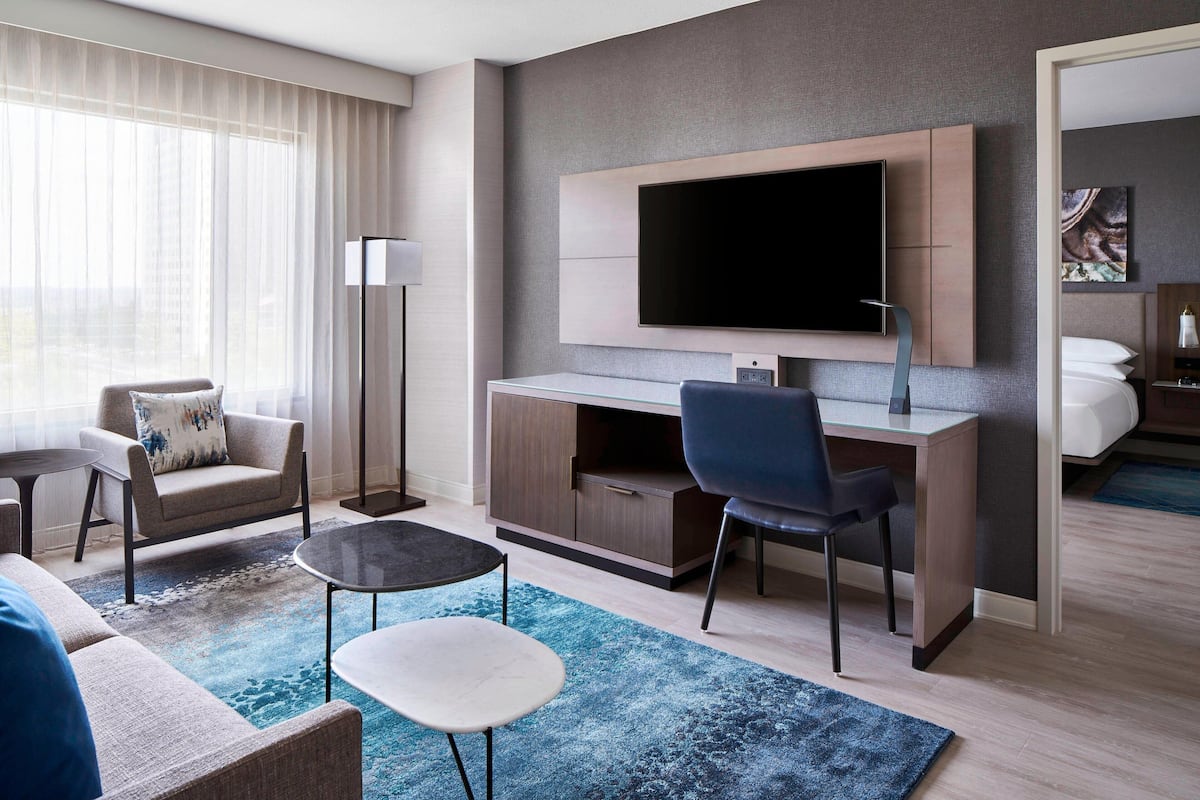 Une chambre d’hôtel moderne équipée d’une télévision à écran plat, d’un bureau, d’un canapé confortable et d’une petite table basse.