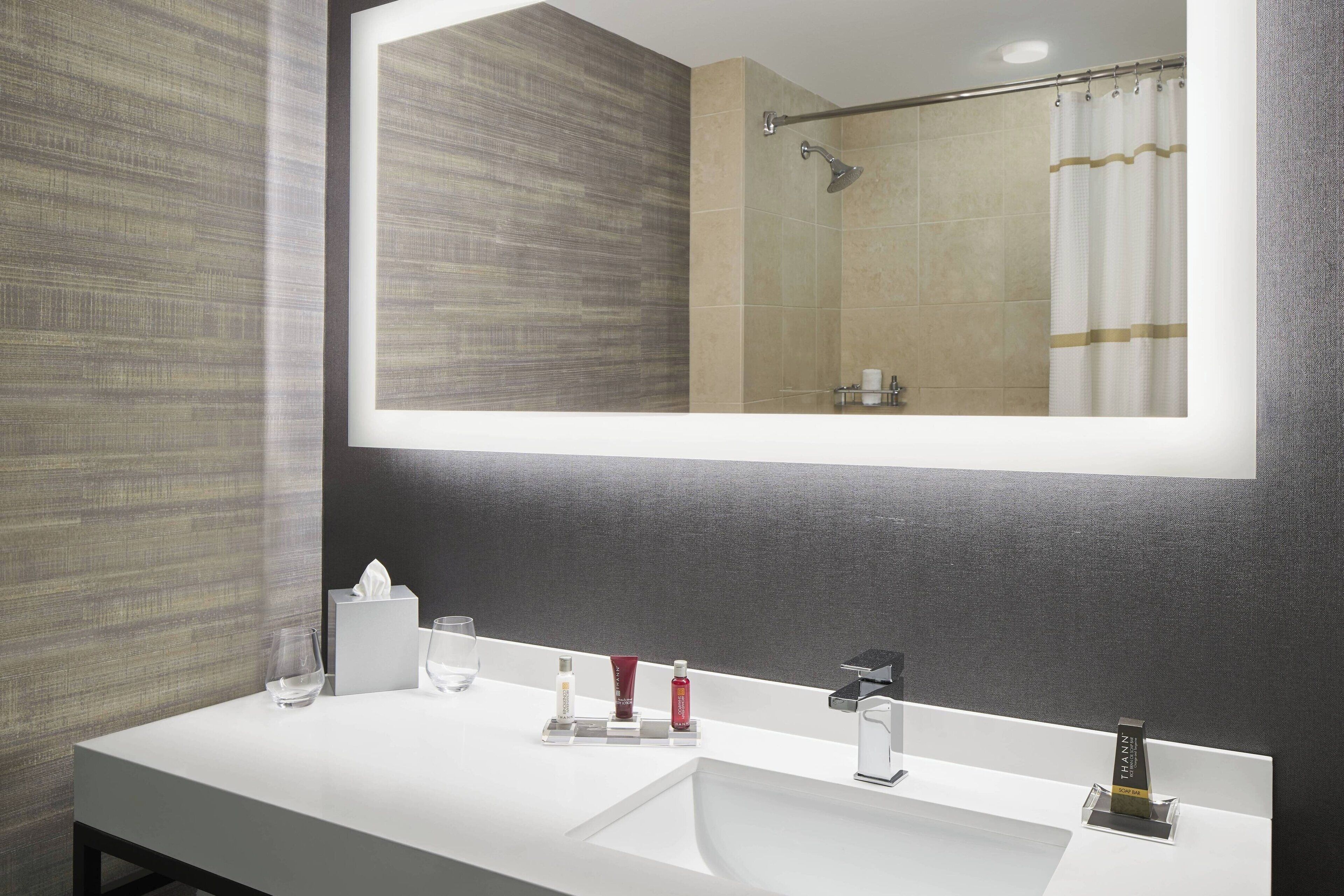 Un bany modern amb un mirall gran, un lavabo blanc i una zona de dutxa.