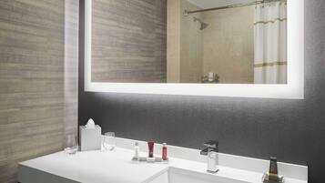 Un bany modern amb un mirall gran, un lavabo blanc i una zona de dutxa.
