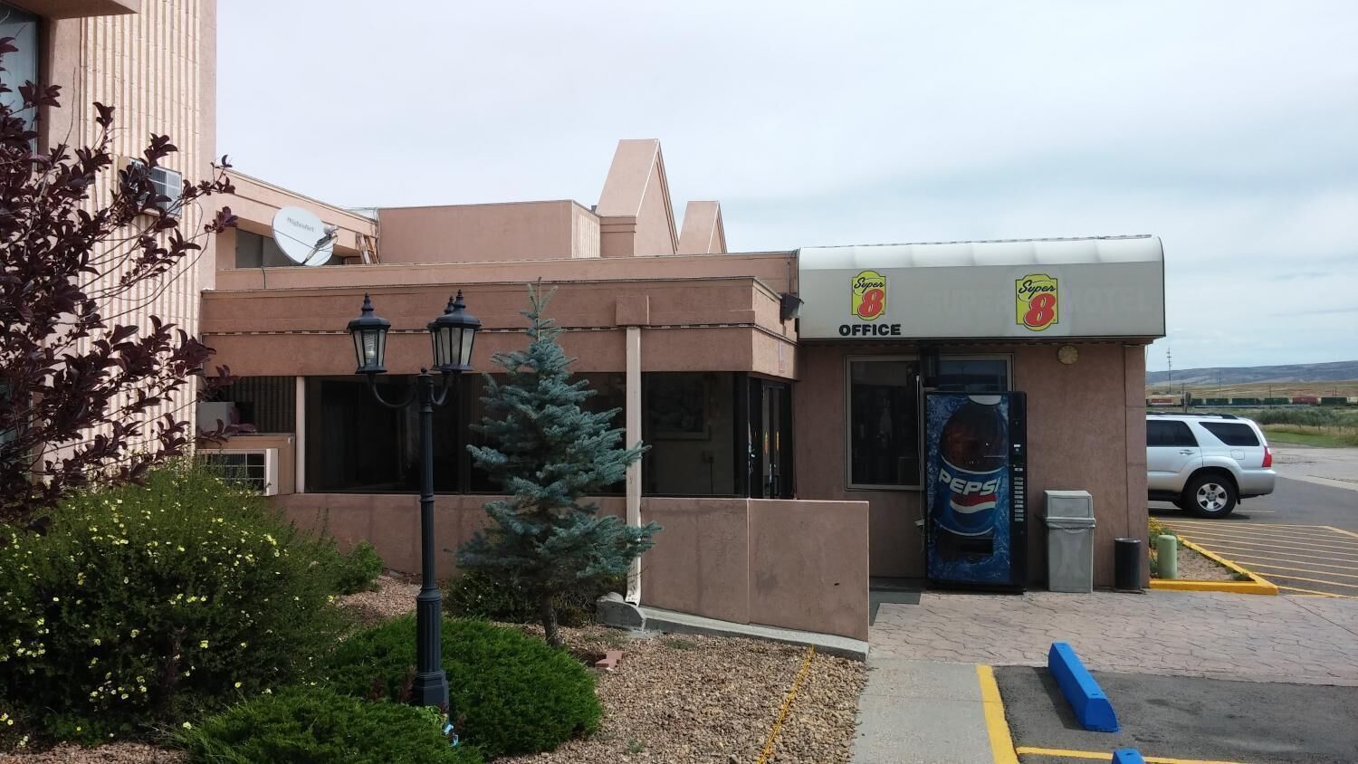 A building with a beige facade, a 'Super 8 Office' sign, and a Pepsi vending machine.