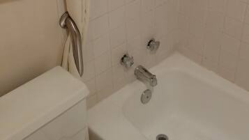 Un baño con bañera, inodoro y un perchero para toallas.