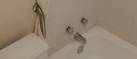 A bathroom with a bathtub, toilet, and a towel rack.