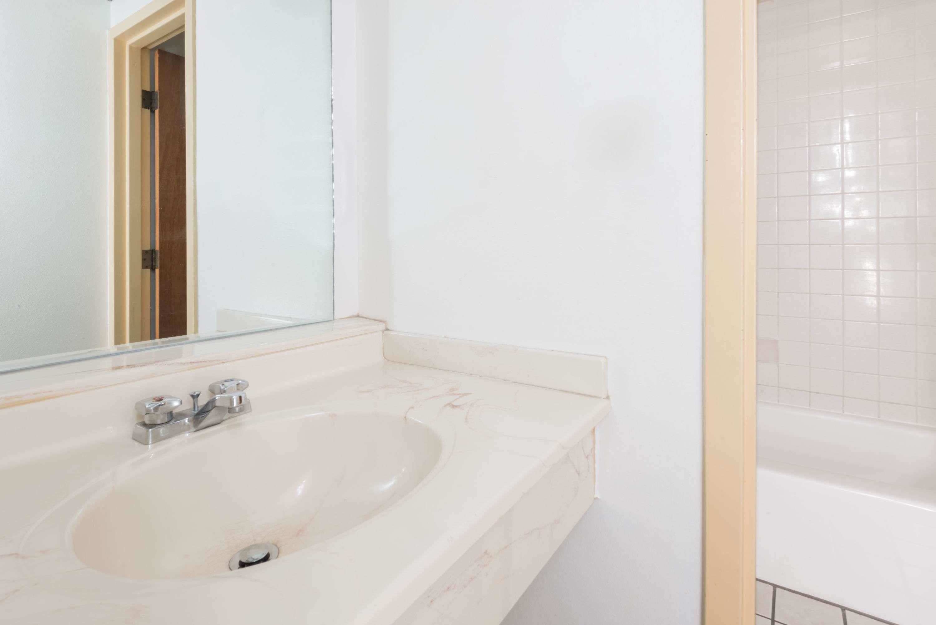 Un baño con lavamanos blanco, espejo y bañera.