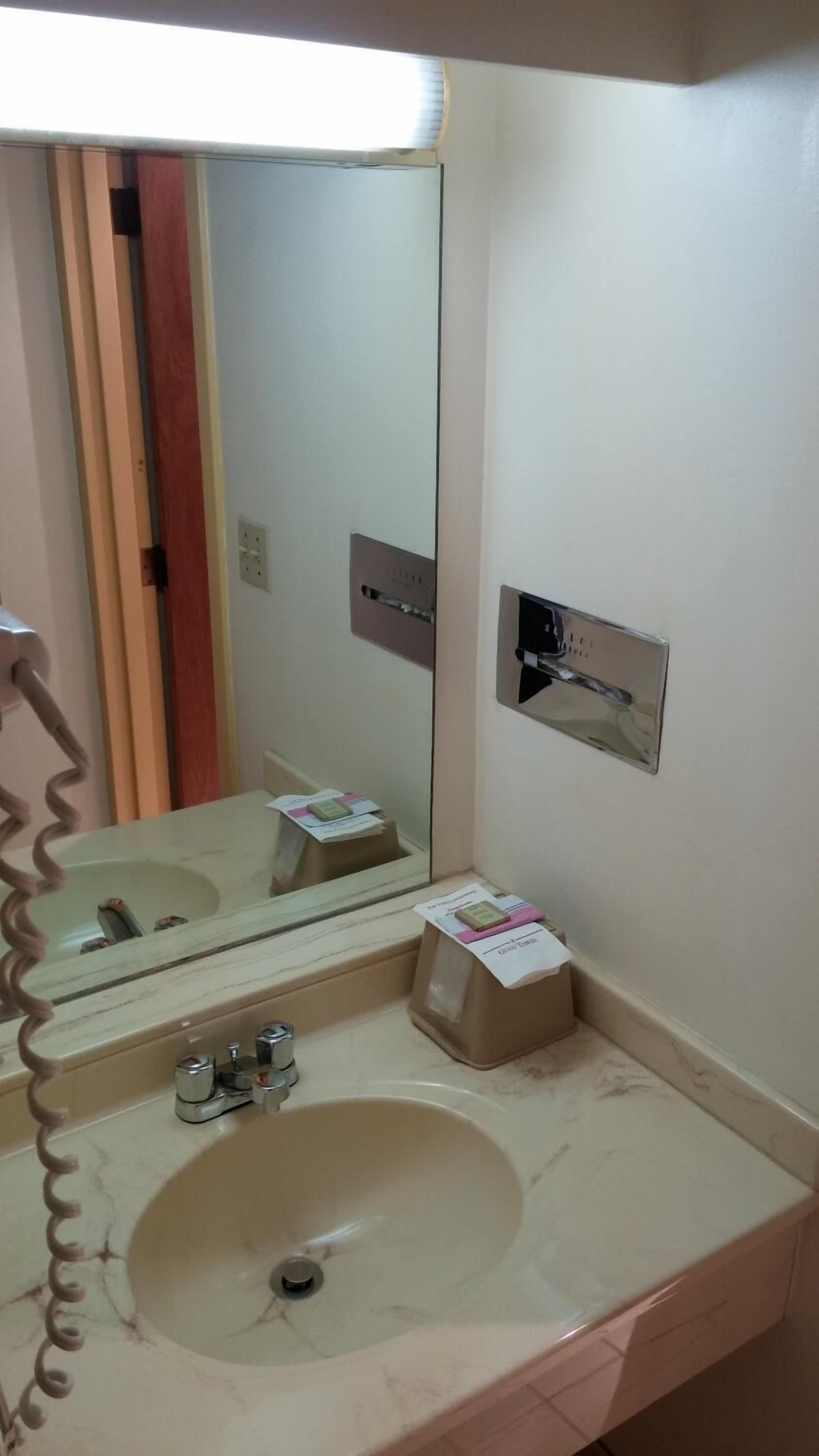 Une salle de bain équipée d’un lavabo, d’un miroir et d’un distributeur de serviettes.