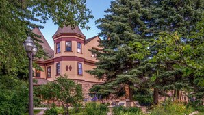 Un edificio grande e histórico con una torre destacada y un jardín bien cuidado.