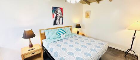 A bedroom with a bed, two bedside tables, a ceiling fan, and a wall-mounted picture.