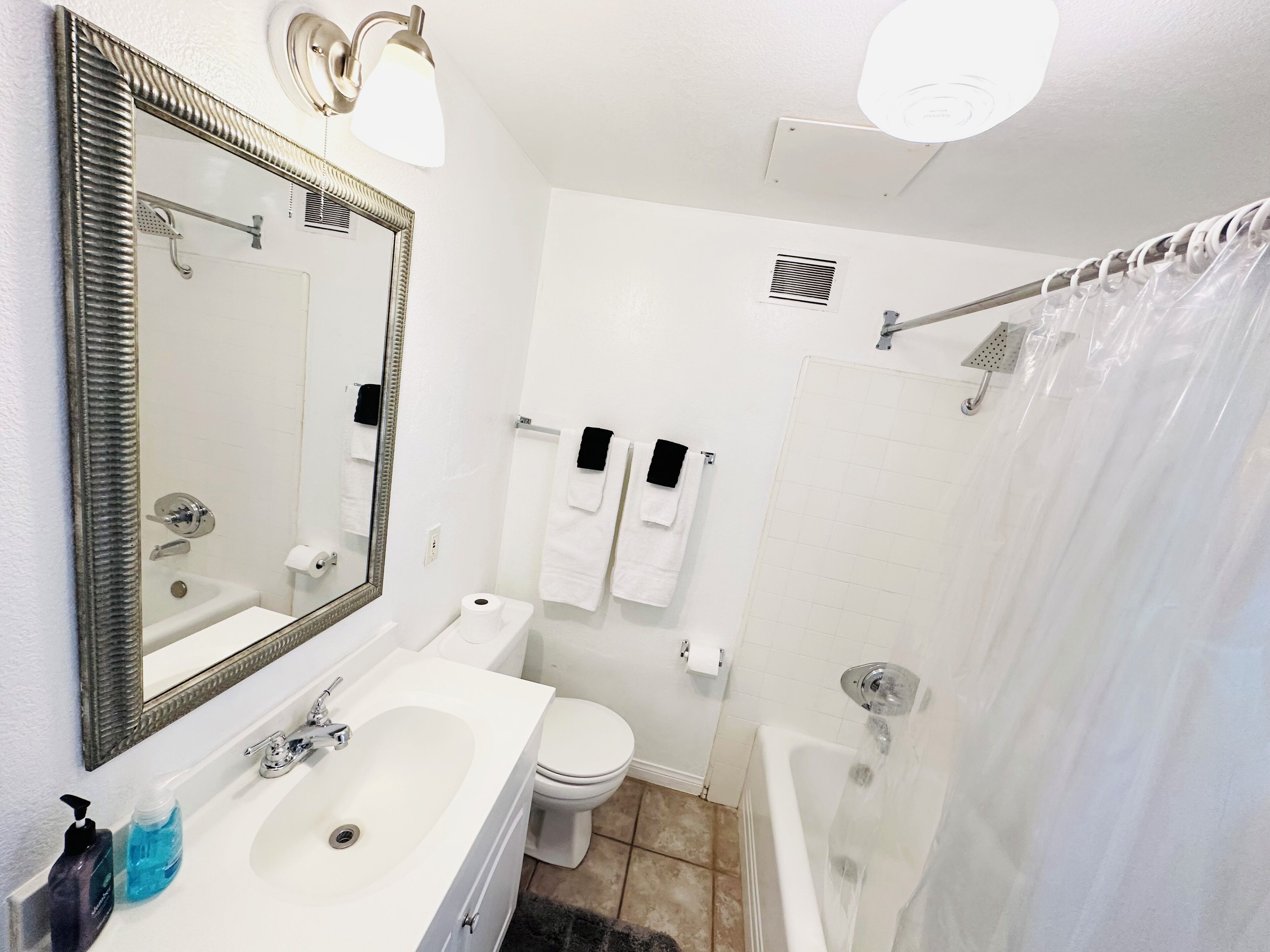 A bathroom with a large mirror, a sink, a toilet, and a bathtub.