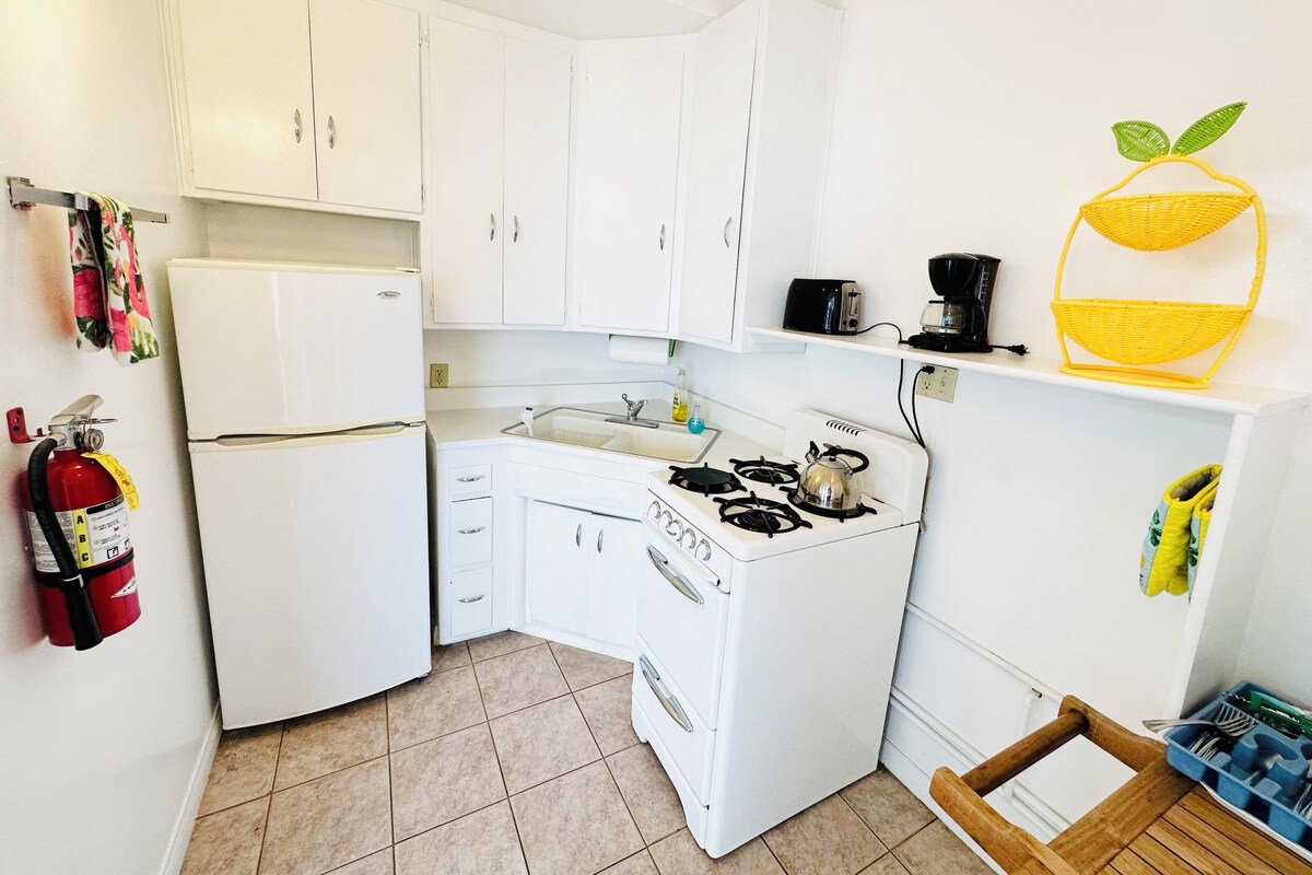 A compact kitchen with white appliances, a gas stove, a sink, and a small countertop.