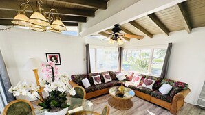 A cozy living room with a sectional sofa, wicker chairs, a glass coffee table, and a ceiling fan. - A Place In The Sun - Adults Only (Palm Springs)