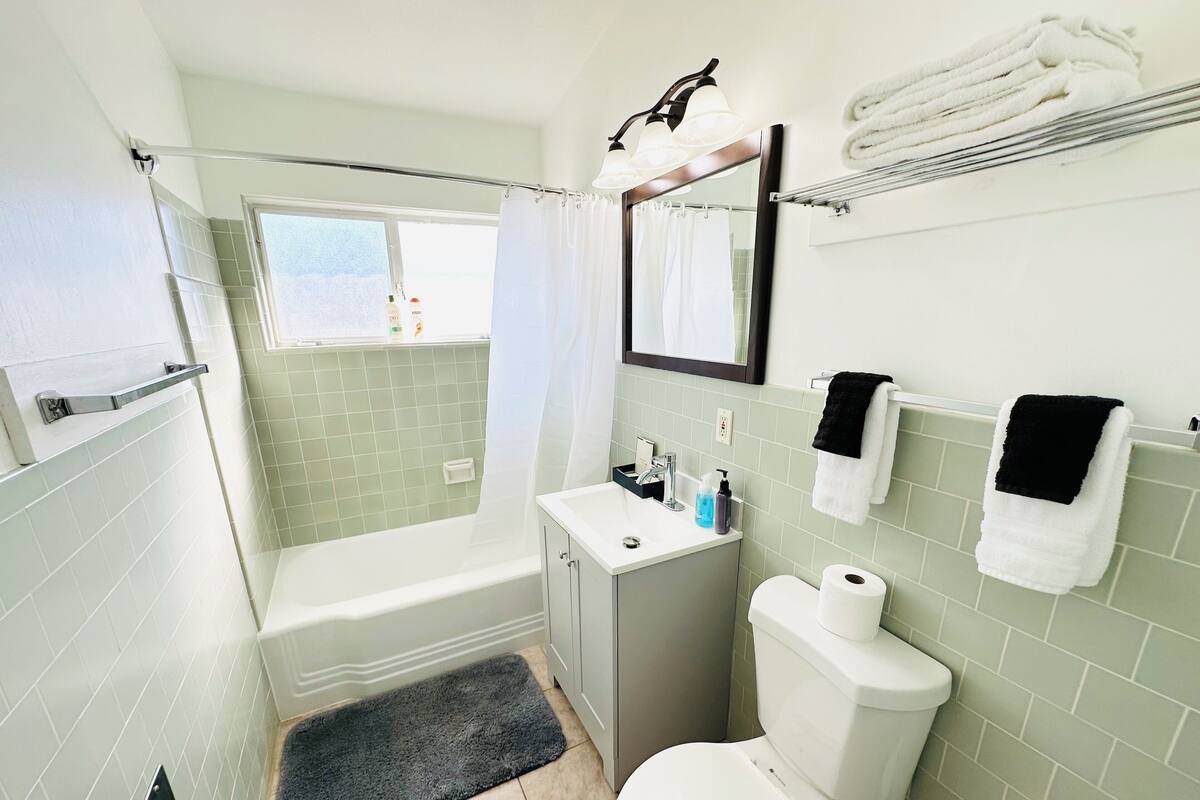 A bathroom with a bathtub, toilet, sink, and a window.