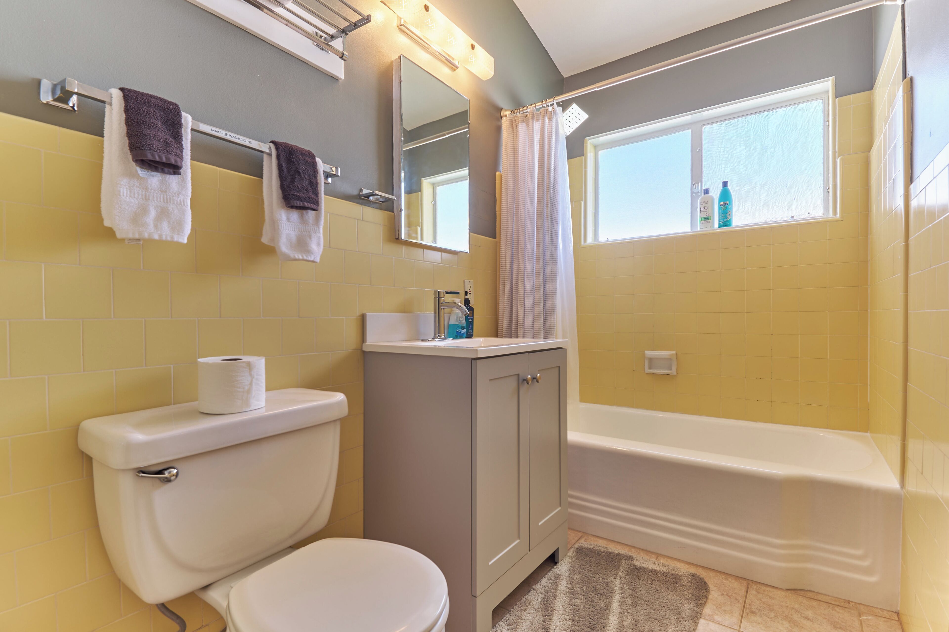 Un baño con inodoro, lavamanos, espejo y bañera.