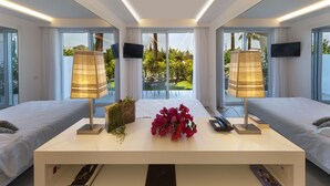 A modern hotel room with two beds, a central table with a lamp, a vase of flowers, and a TV on the wall. - Hotel Alpha (Sant'Agnello)