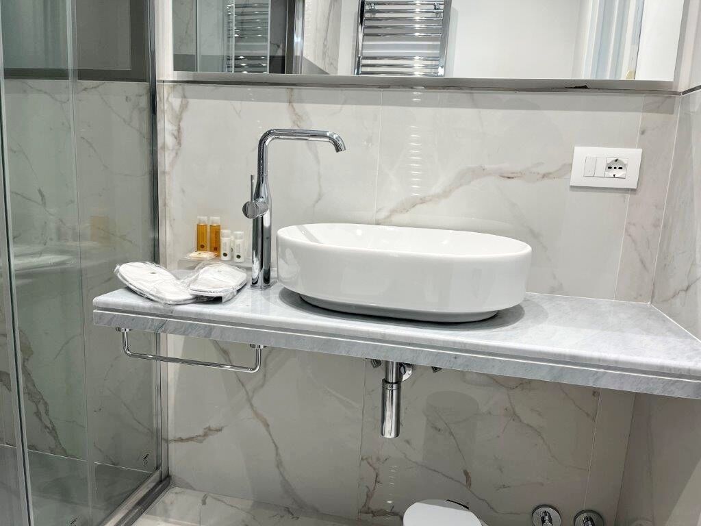A bathroom with a white sink, chrome faucet, and a glass shower enclosure.