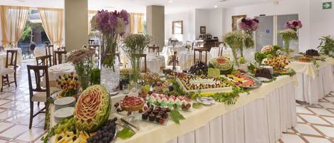 A buffet table with a variety of food items and decorative flowers.