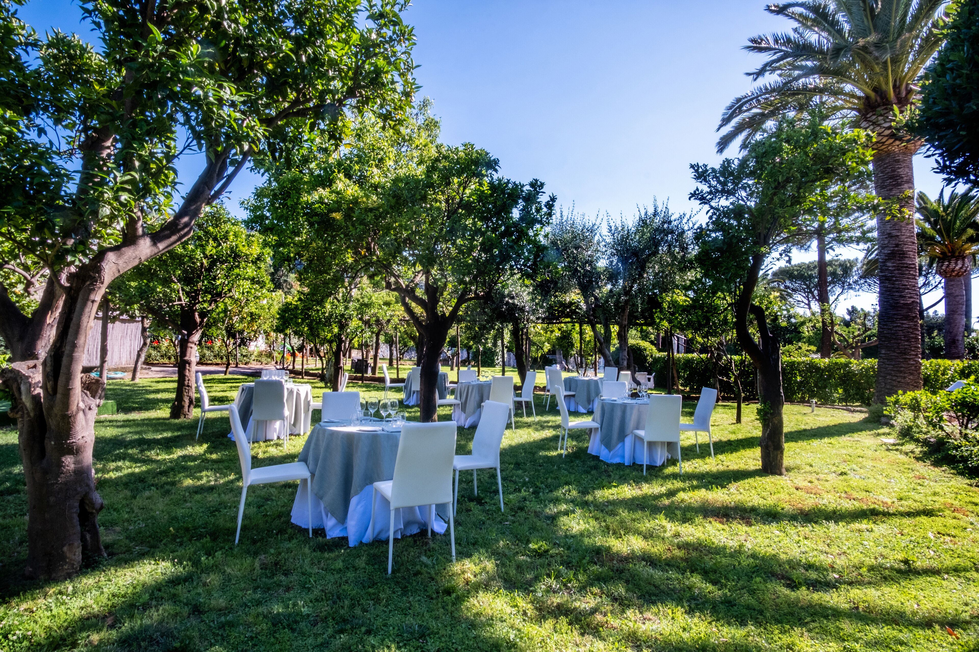 An outdoor garden setting with tables and chairs arranged for dining.