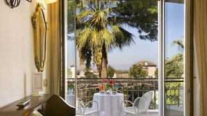 A balcony with a white table, chairs, and a palm tree view. - Hotel Alpha (Sant'Agnello)