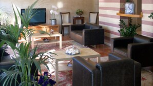 A modern living room with a television, comfortable seating, and decorative plants. - Vittoria Hotel (Rubano)