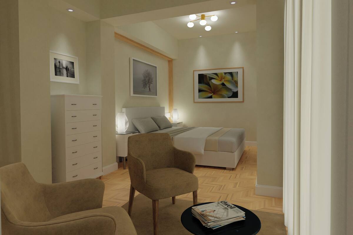 A modern living room with a sofa, two armchairs, a coffee table, and a bed.