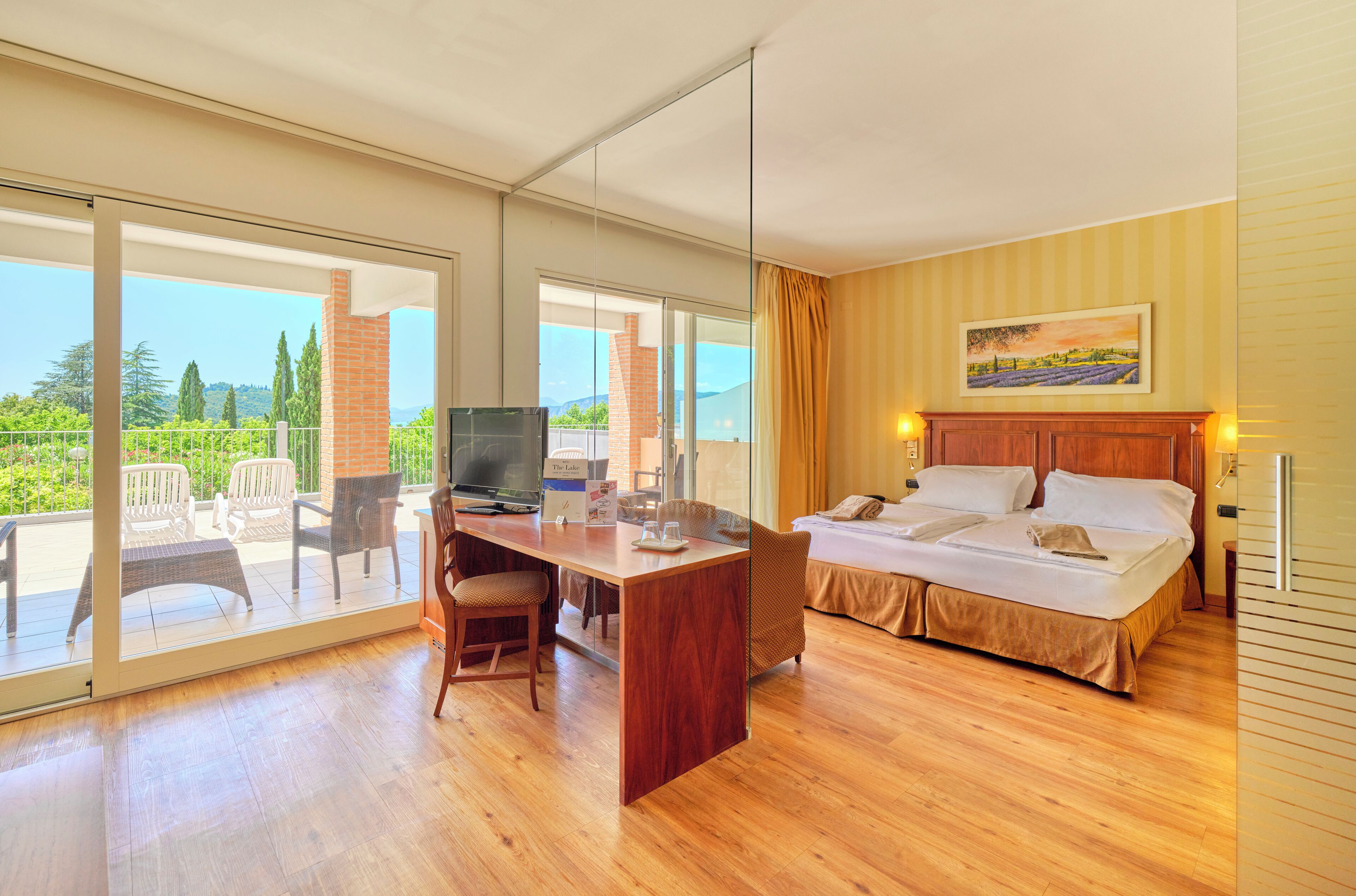 A hotel room with a bed, a desk, a chair, and a TV.