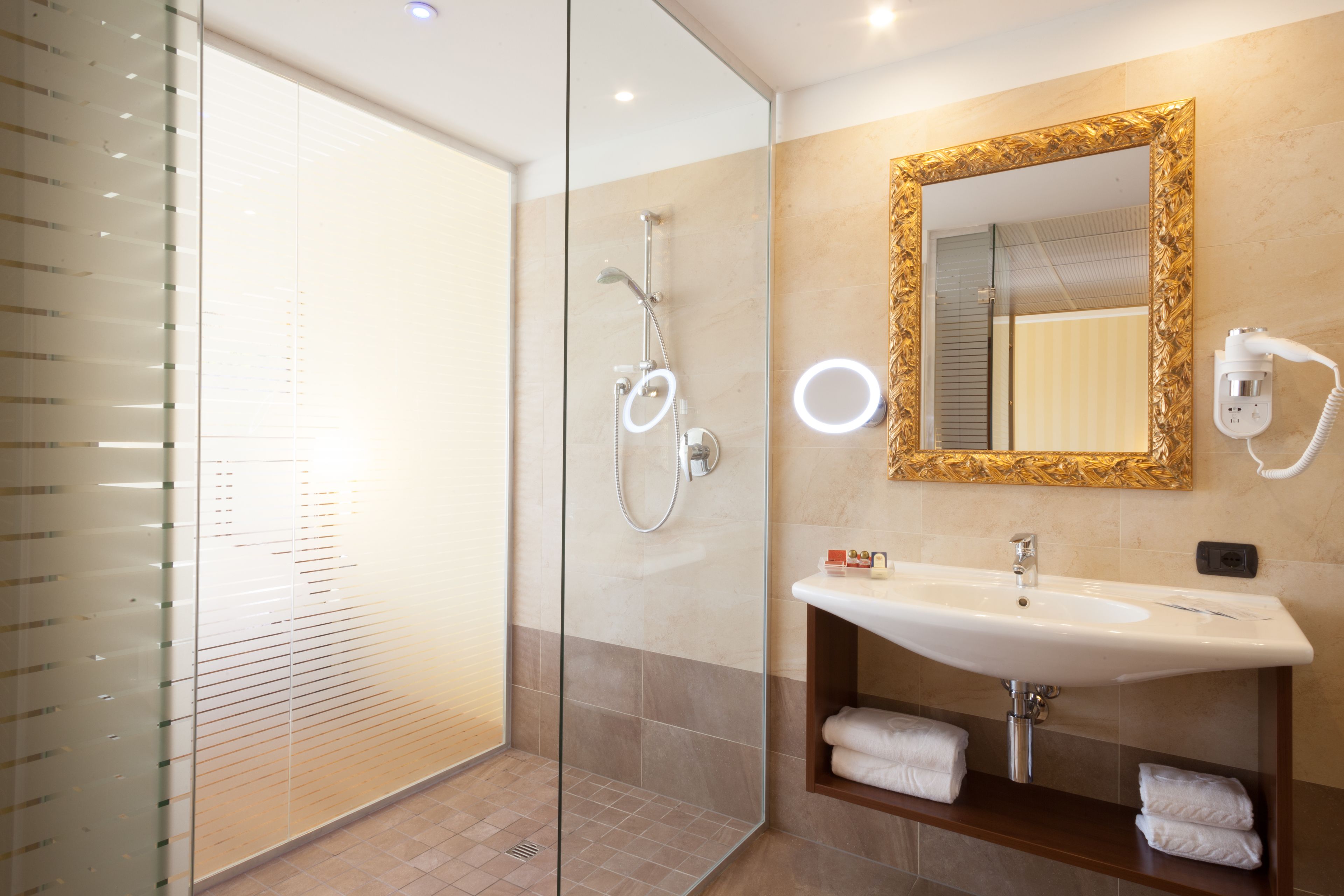 A modern bathroom with a glass shower enclosure, a vanity with a sink and mirror, and a towel rack.