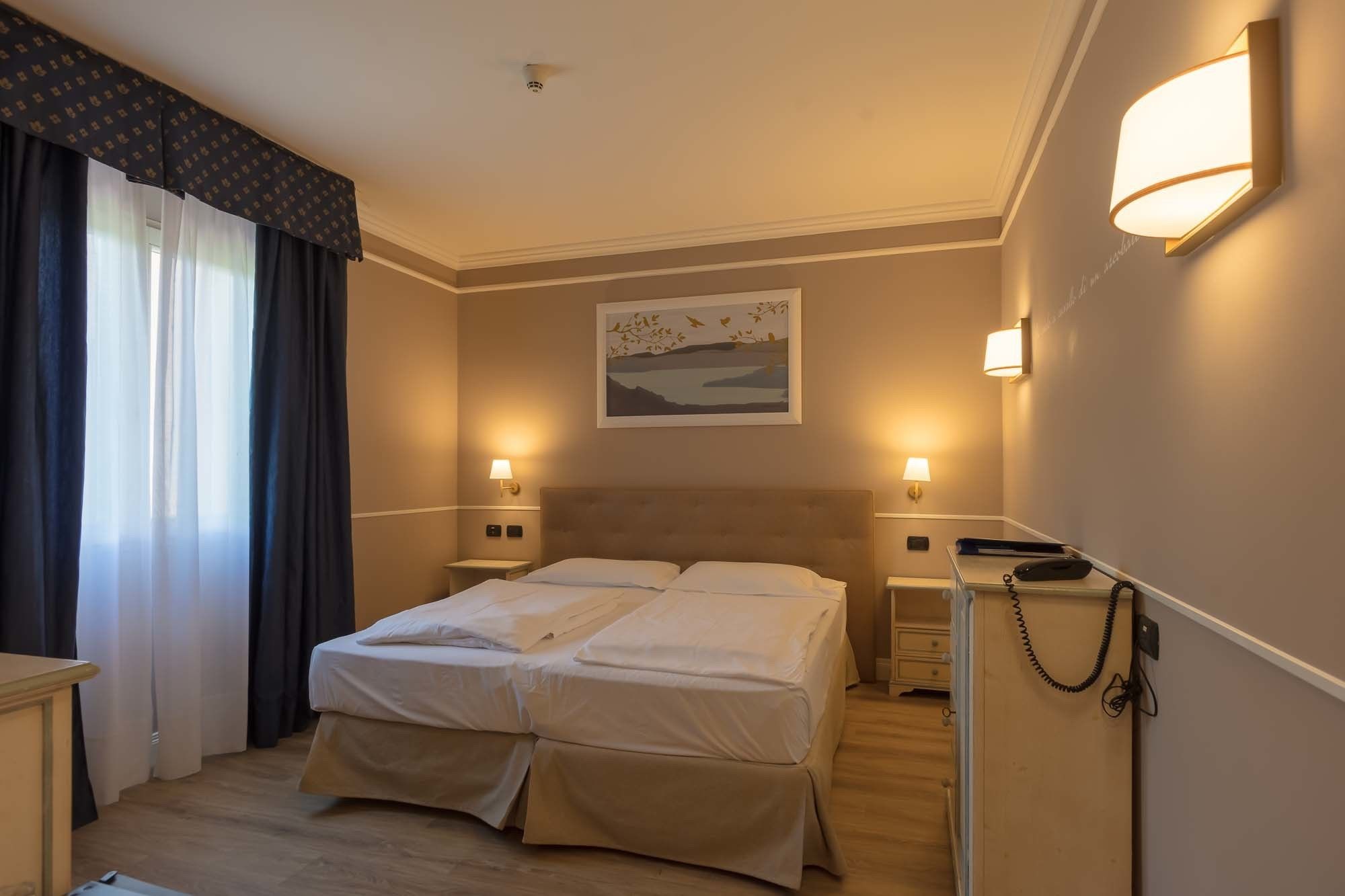 Een hotelkamer met twee bedden, een bureau en een nachtkastje.
