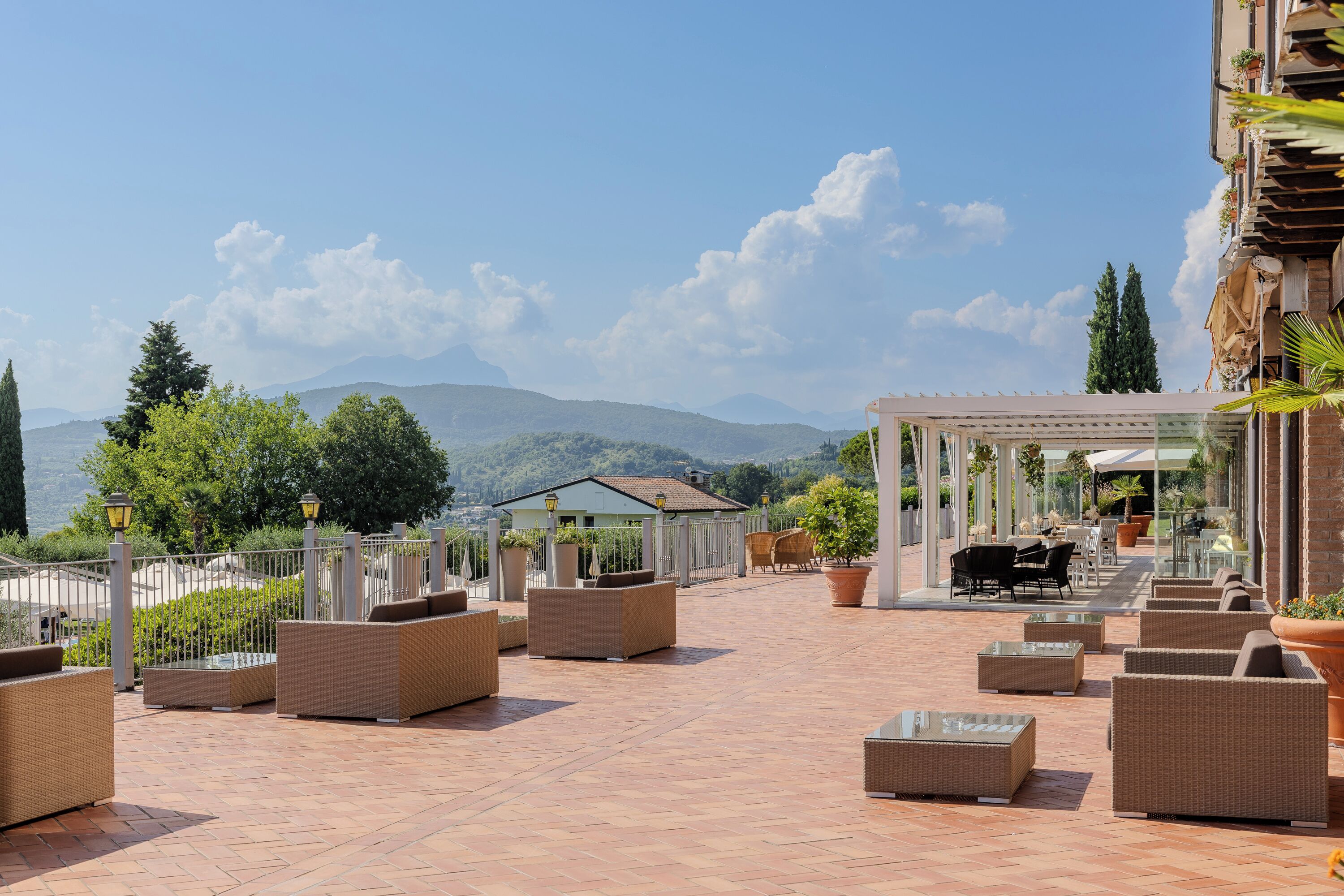An outdoor patio with wicker furniture, a glass-top table, and a pergola.