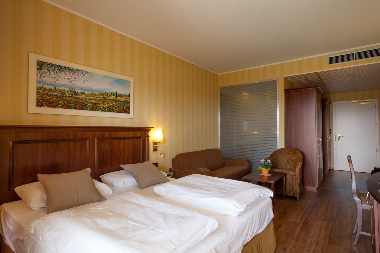 Habitación de hotel con dos camas, un sofá, una mesa de comedor y un cuadro en la pared.
